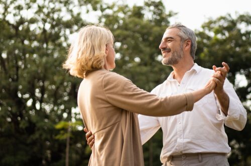 Ein älteres, elegantes kaukasisches Paar tanzt und schaut einander an, fühlt Liebe und Wertschätzung zu ihrem Jubiläum im Park