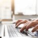 Haende tippen auf Laptop im hellen Buero, symbolisch fuer ghostwriter bachelorarbeit und professionelle Schreibunterstuetzung